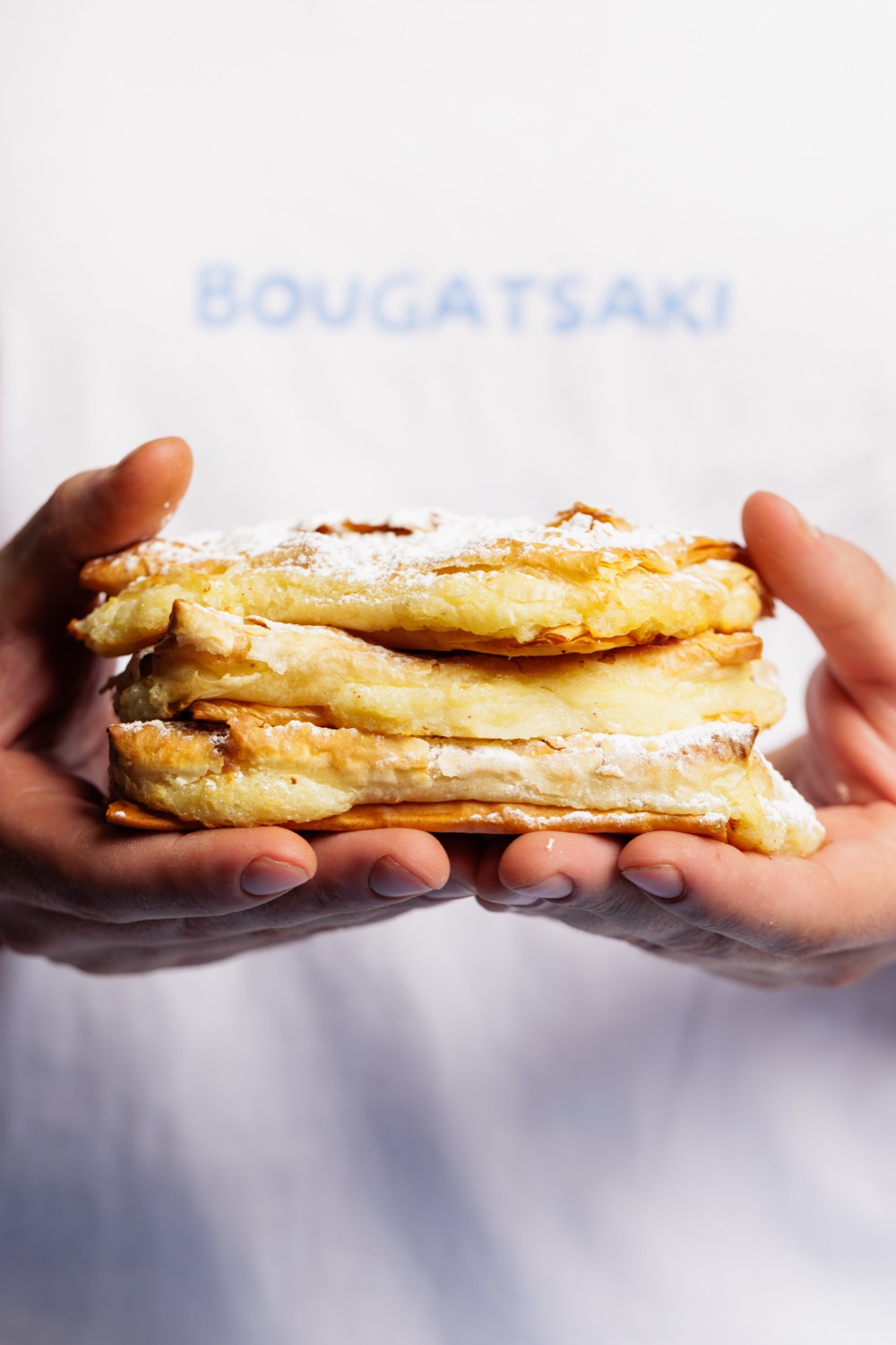 Hands holding a fresh stack of bougatsa